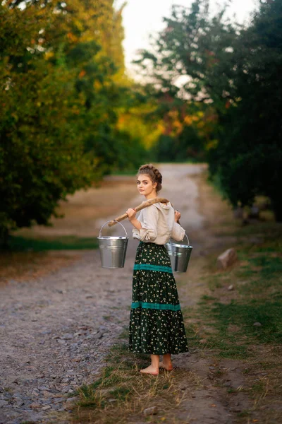 Kırsal Kesimdeki Uzun Elbiseli Güzel Sarışın Kız Ellerinde Kova Dolusu — Stok fotoğraf