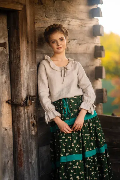 Kırsal kesimde uzun elbiseli, örülmüş güzel bir kız köyde poz veriyor. Kırsal kesimdeki sanat fotoğraflarında oldukça genç bir model.. 