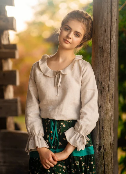 Kırsal kesimde uzun elbiseli, örülmüş güzel bir kız köyde poz veriyor. Kırsal kesimdeki sanat fotoğraflarında oldukça genç bir model.. 