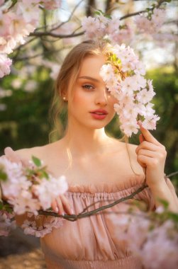 Renkli çiçeklerin yanında duran pembe, klasik elbiseli güzel kız. Romantik bir kadının sanat eseri. Çiçek parkında poz veren güzel bir şefkat modeli..