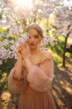 Renkli çiçeklerin yanında duran pembe, klasik elbiseli güzel kız. Romantik bir kadının sanat eseri. Çiçek parkında poz veren güzel bir şefkat modeli..
