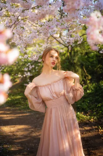 stock image Beautiful  girl in pink vintage dress standing near colorful flowers. Art work of romantic woman .Pretty tenderness model posing  in blossom park.
