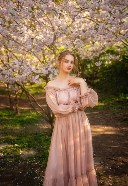 Renkli çiçeklerin yanında duran pembe, klasik elbiseli güzel kız. Romantik bir kadının sanat eseri. Çiçek parkında poz veren güzel bir şefkat modeli..