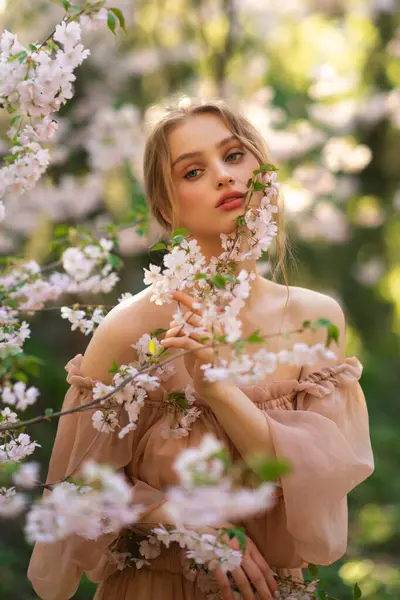 Renkli çiçeklerin yanında duran pembe, klasik elbiseli güzel kız. Romantik bir kadının sanat eseri. Çiçek parkında poz veren güzel bir şefkat modeli..