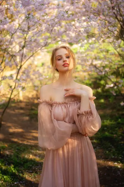 漂亮的女孩穿着粉红色的老式衣服站在五彩缤纷的花朵旁边 浪漫女人的艺术作品 花圃中的美丽柔情模型 免版税图库照片