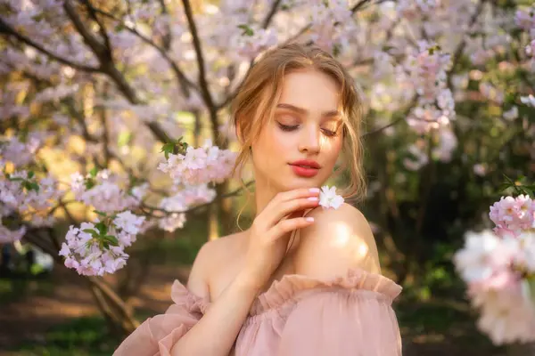 漂亮的女孩穿着粉红色的老式衣服站在五彩缤纷的花朵旁边 浪漫女人的艺术作品 花圃中的美丽柔情模型 图库图片