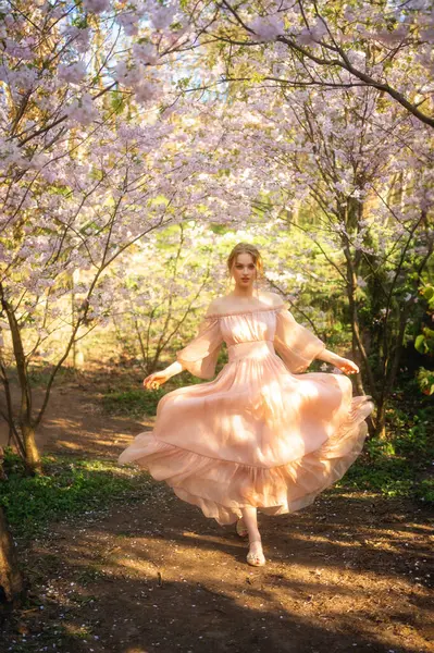 漂亮的女孩穿着粉红色的老式衣服站在五彩缤纷的花朵旁边 浪漫女人的艺术作品 花圃中的美丽柔情模型 免版税图库图片