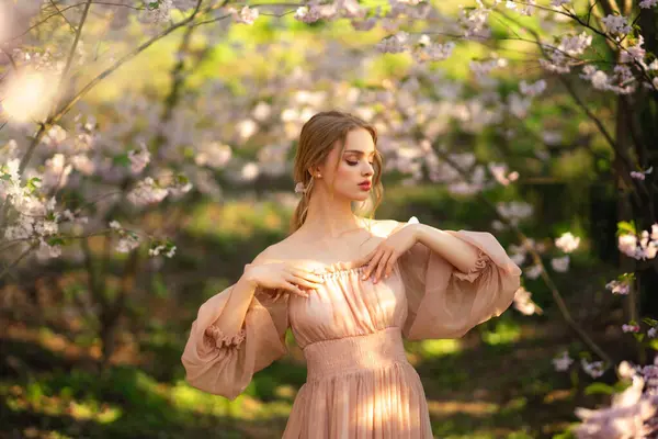 漂亮的女孩穿着粉红色的老式衣服站在五彩缤纷的花朵旁边 浪漫女人的艺术作品 花圃中的美丽柔情模型 图库照片