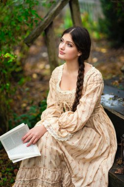 Oldukça uzun saçlı, esmer, esmer, eskimiş dantel elbiseli bir kız. Şefkatli romantik model.