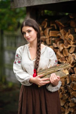 Kırsal kesimde, uzun Ukrayna elbisesi içinde doğa üzerinde çalışan güzel esmer kız. Kırsal kesimdeki sanat fotoğraflarında oldukça genç bir model.. 