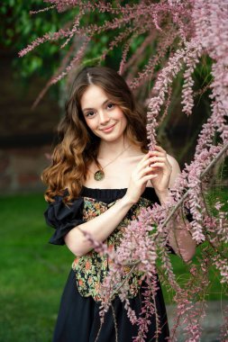 Çiçekli leylak bahçesinde poz veren klasik korse giymiş romantik bir kadın.