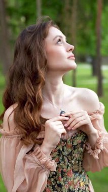 Çiçekli leylak bahçesinde poz veren klasik korse giymiş romantik bir kadının videosu.