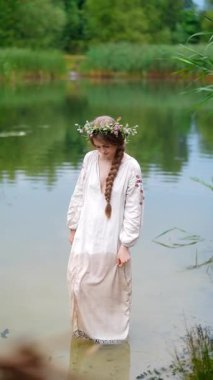 Ukrayna 'nın geleneksel etnik kıyafetleri içinde iki genç kadın fotoğraf çekimi sırasında nehirde duruyor.