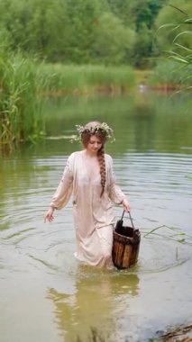 Ukrayna 'nın geleneksel etnik kıyafetleri içinde iki genç kadın fotoğraf çekimi sırasında nehirde duruyor.