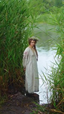 Ukrayna 'nın geleneksel etnik kıyafetleri içinde iki genç kadın fotoğraf çekimi sırasında nehirde duruyor.