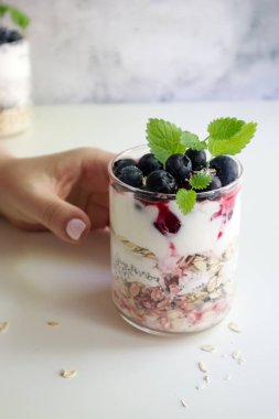 Bir el, Chia tohumları, yulaf ezmesi ve böğürtlenli sağlıklı bir kahvaltı için uzanır.