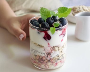 Bir el, Chia tohumları, yulaf ezmesi ve böğürtlenli sağlıklı bir kahvaltı için uzanır.