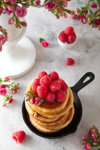Pancakes with honey decorated with raspberries and flowers top view