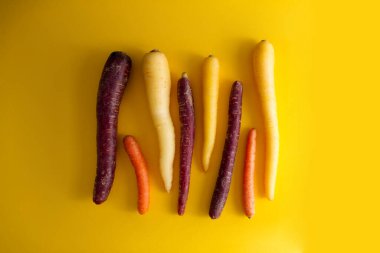 Gökkuşağı havuçları sarı arka plan görünümünde birbirine paralel sıralanmış. 