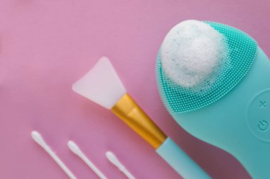 Pembe arka planda silikon yüz fırçası ve farklı kozmetik aletler. Yüksek kalite fotoğraf