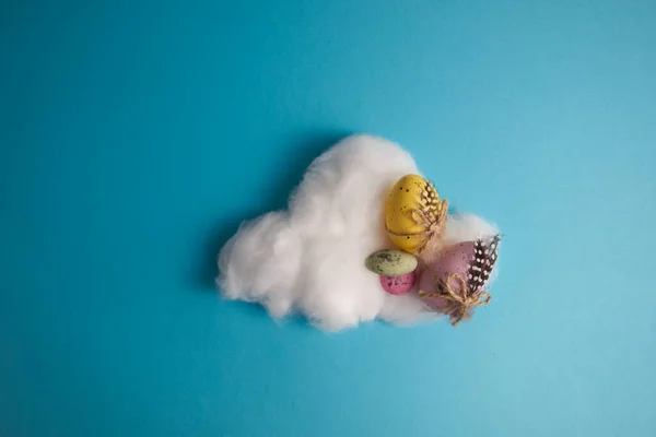 Decorated Easter eggs and candies on a cloud of cotton wool on a blue background. High quality photo