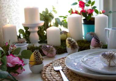 Festive table setting and spring decor with candles, easter eggs and flowers. High quality photo