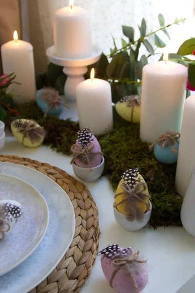 Festive table setting and spring decor with candles, easter eggs and flowers. High quality photo