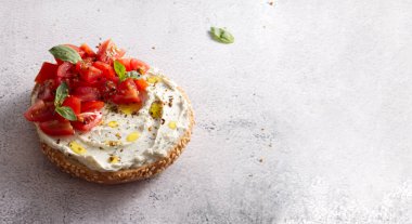 Bun with sesame seeds with cheese cream and fresh tomatoes with basil leaves copy space
