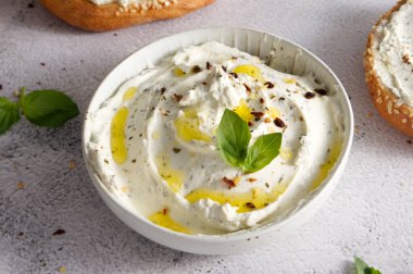 Cheese curd spread for breakfast with herbs, sun-dried tomatoes, olive oil and sandwiches close-up