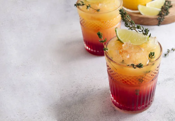 Cocktails with ice, orange juice and grenadine syrup decorated with berries and herbs copy space