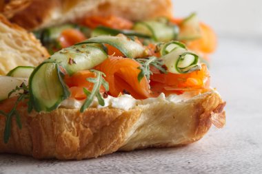 Croissants with cheese cream, red fish and cucumber close up . High quality photo