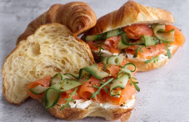 Croissants with cheese cream, red fish and cucumber close up . High quality photo