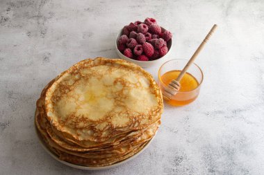 Masanın üzerinde bal ve ahududulu taze krep yığını var. Yüksek kalite fotoğraf
