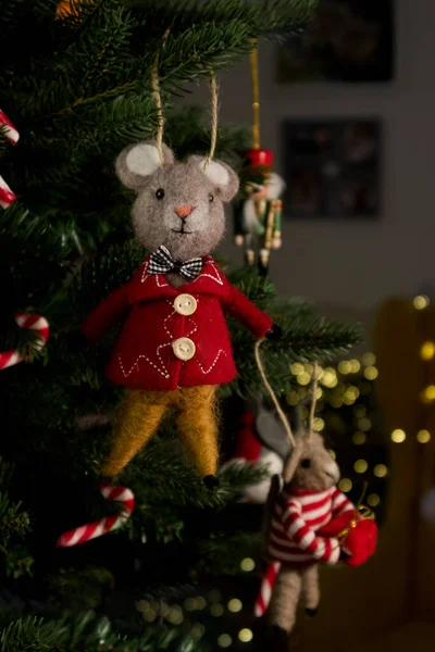 Felted wool mouse on a Christmas tree against a background of Christmas lights. High quality photo