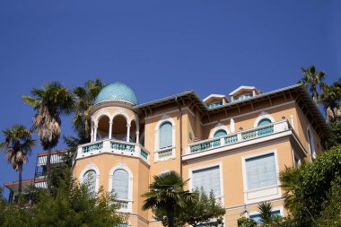 Yeşil çiçekli bir bahçe ve palmiye ağaçlarıyla çevrili antik bir İtalyan villası manzarası. Yüksek kalite