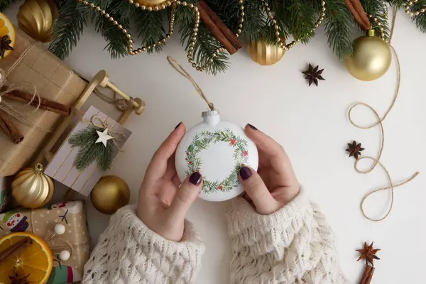 Eller Noel ağacı topunu Noel dekorunda beyaz bir arka planda tutuyor.