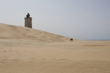 Geniş Kum tepelerindeki Deniz fenerine Yürüyen İnsanlar