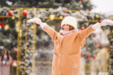 Genç, mutlu bir kadın yılbaşı zamanı dışarıda, Noel ışıklarının önünde. Tatiller, dinlenme, seyahat konsepti.