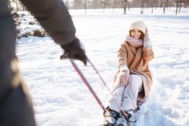 Kış karlı ormanlarda bir adam bir kadını kızağa sarar. Soğuk hava. Tatiller, dinlenme, seyahat konsepti.