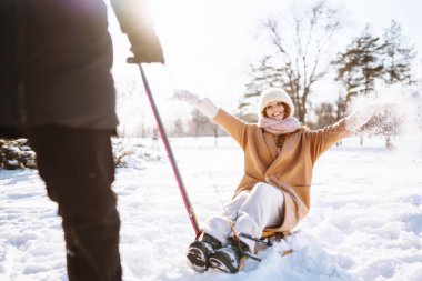 Kış karlı ormanlarda bir adam bir kadını kızağa sarar. Soğuk hava. Tatiller, dinlenme, seyahat konsepti.