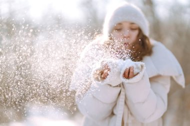 Genç bir kadın güneşli kış gününde bir karla oynar. Soğuk hava. Tatiller, dinlenme, seyahat konsepti.