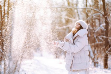 Genç bir kadın güneşli kış gününde bir karla oynar. Soğuk hava. Tatiller, dinlenme, seyahat konsepti.