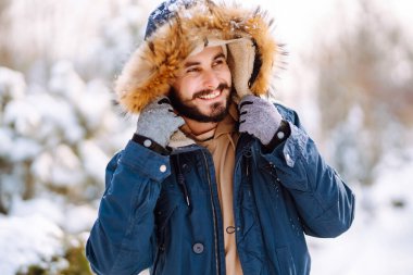 Kış parkında kameraya gülümseyen sakallı adam. Sezon, Noel, seyahat ve insanlar konsepti.