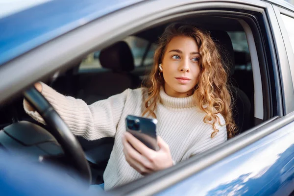 一个年轻女子开车时用智能手机发短信的肖像 汽车共享 租赁服务或出租车应用程序 — 图库照片