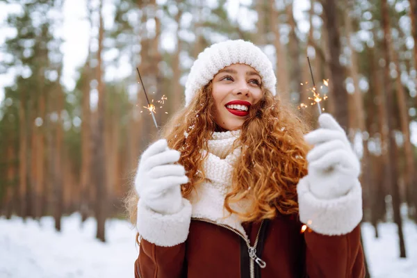 在冬天的森林里 一个快乐的年轻女人牵着一个闪光的手 — 图库照片