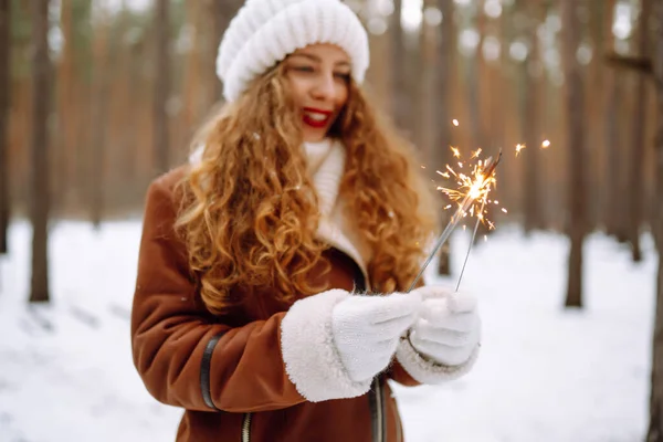在冬天的森林里 一个快乐的年轻女人牵着一个闪光的手 — 图库照片