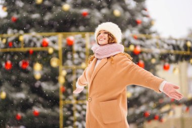 Noel zamanı dışarıda, Noel ışıklarının önünde güzel bir kadın. Tatiller, dinlenme, seyahat konsepti.