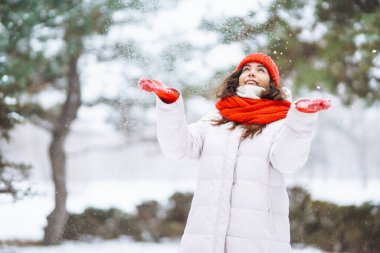 Güzel bir kadın karlı ağaçların arasında duruyor ve ilk karın tadını çıkarıyor. Kış tatilin kutlu olsun. Noel.