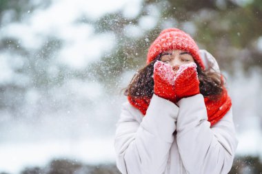 Güzel bir kadın karlı ağaçların arasında duruyor ve ilk karın tadını çıkarıyor. Kış tatilin kutlu olsun. Noel.