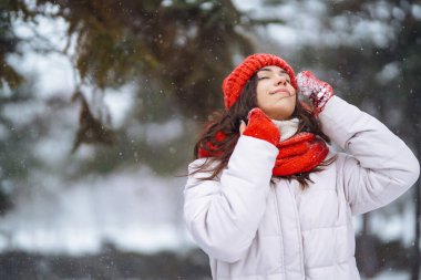 Güzel bir kadın karlı ağaçların arasında duruyor ve ilk karın tadını çıkarıyor. Kış tatilin kutlu olsun. Noel.